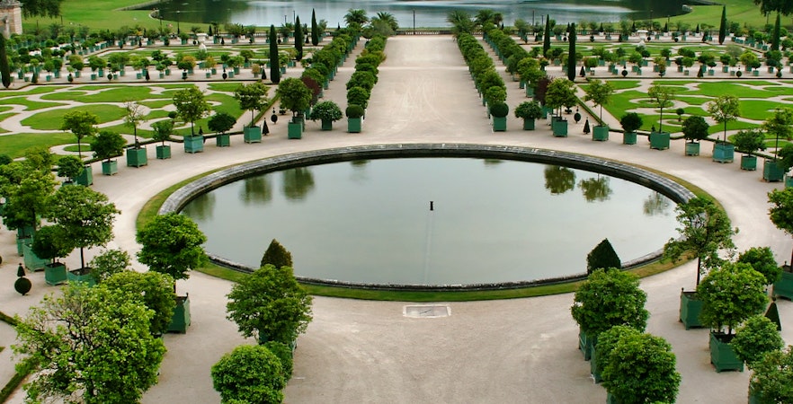 Versailles gardens with symmetrical pathways and central pond, France.