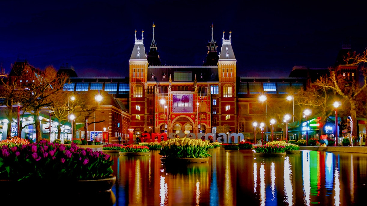 Amsterdam's Rijksmuseum at night with reflections in the canal, viewed during an evening cruise.