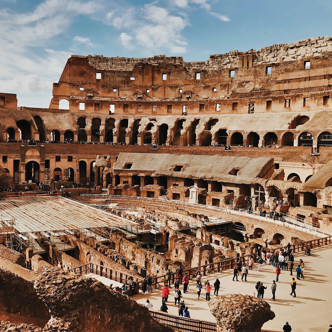 Colosseum interior with tourists exploring ancient Roman architecture in Rome, Italy.