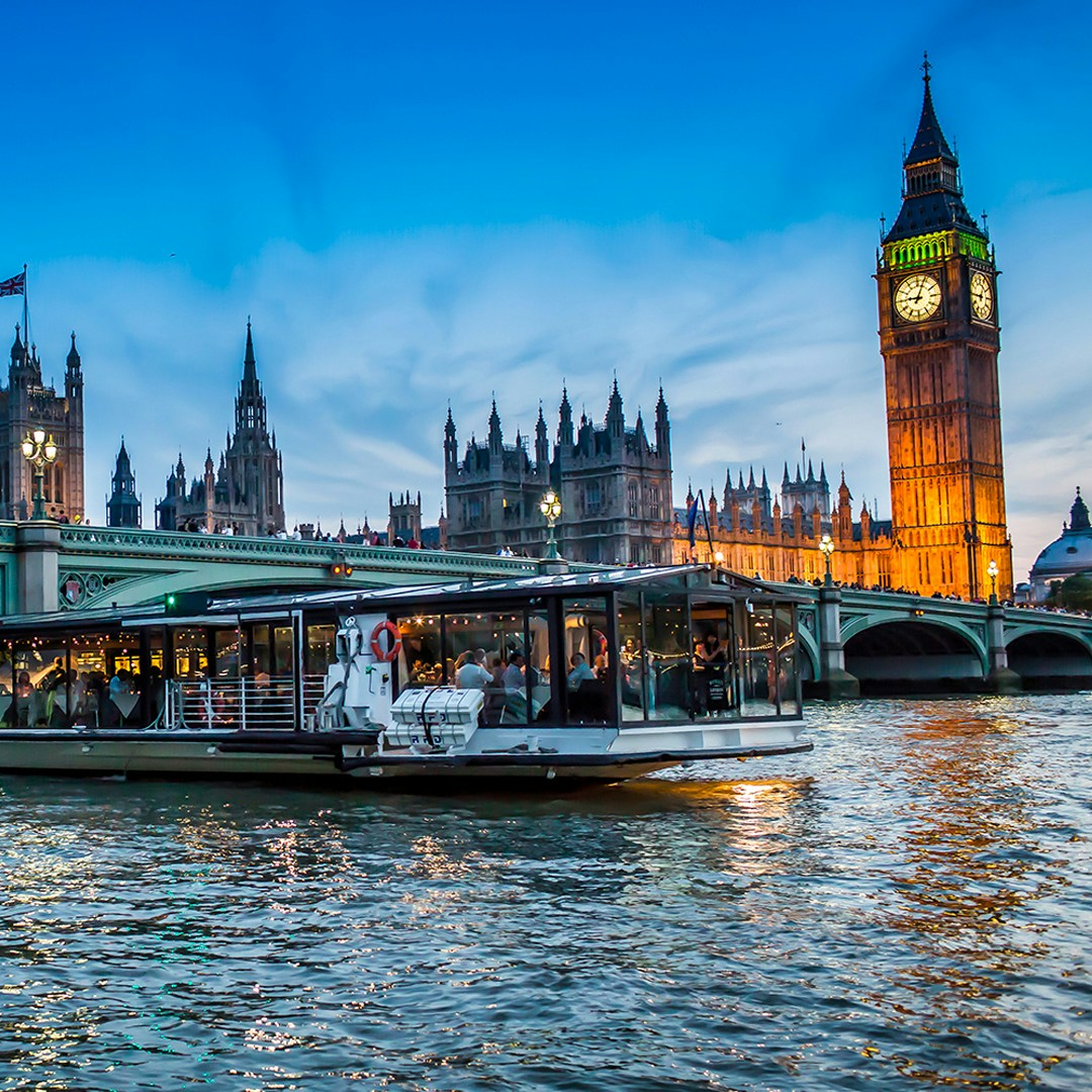 Dinner cruise boat on the Thames with Big Ben and Houses of Parliament in the background, London.