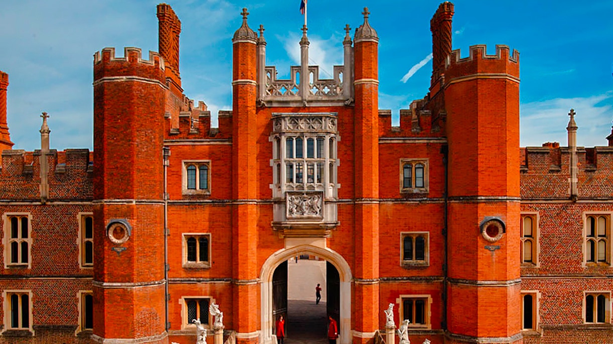 Hampton Court Palace entrance with red brick towers and statues, London, England.