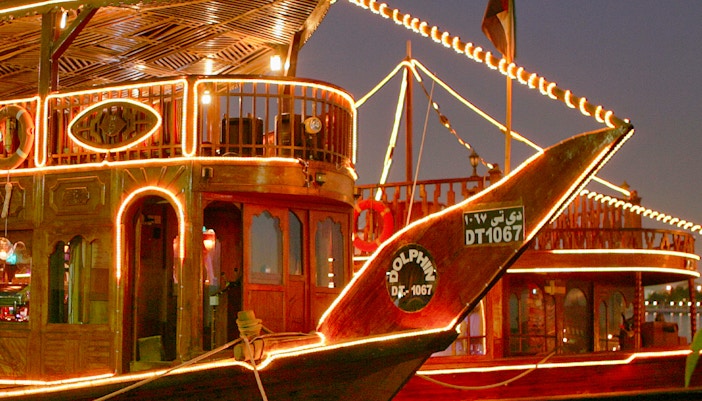 Traditional dhow boat illuminated at night for a dinner cruise on Dubai Creek.