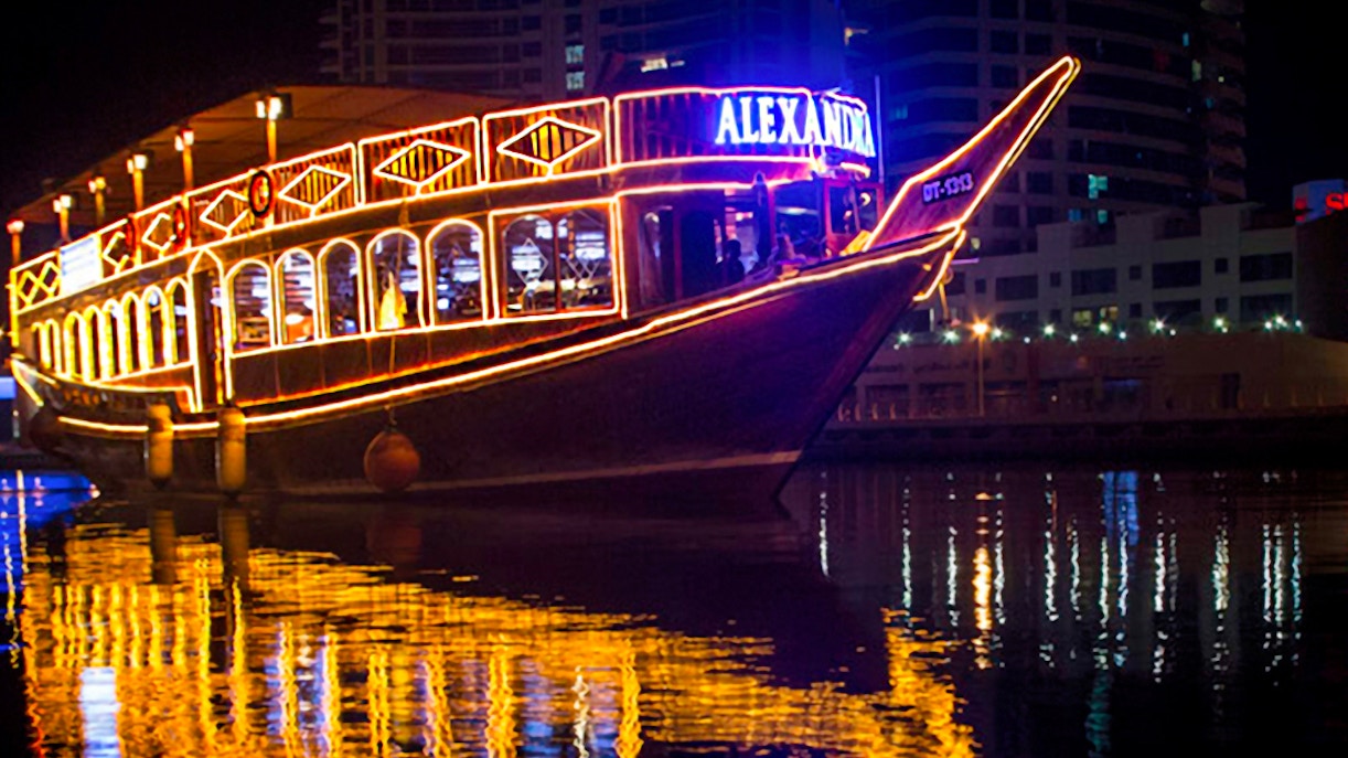 Dhow cruise with lights reflecting on Dubai Marina at night.