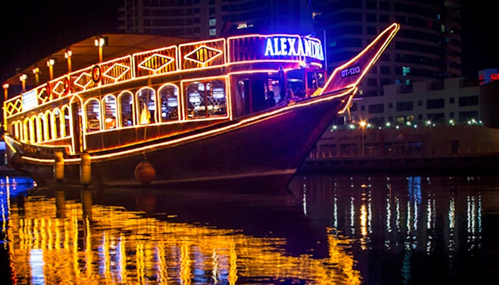 Dhow cruise with lights reflecting on Dubai Marina at night.