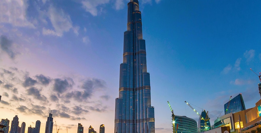 Burj Khalifa at sunset with surrounding Dubai skyline and waterfront.