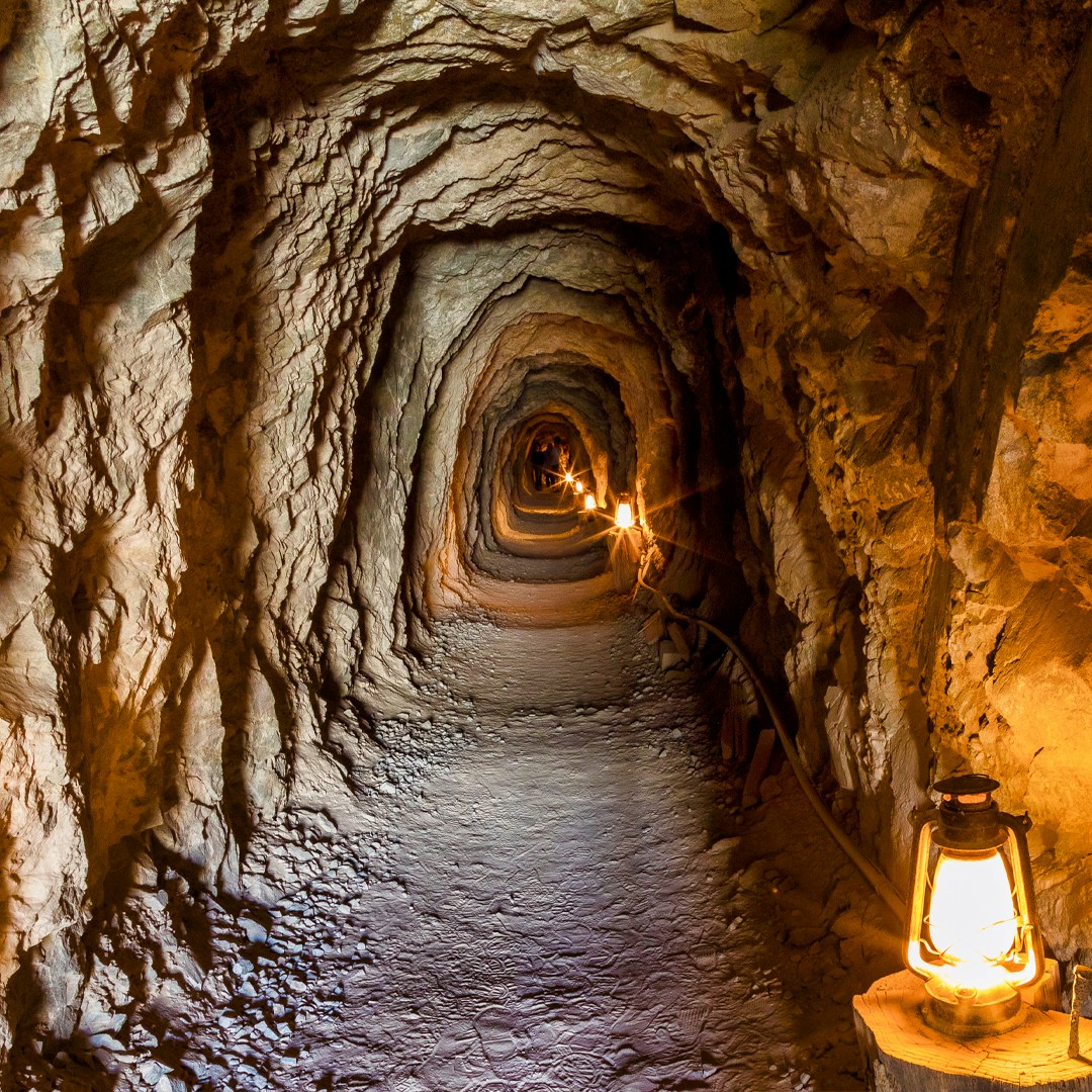 mine tunnel with lanterns illuminating the rocky passage.