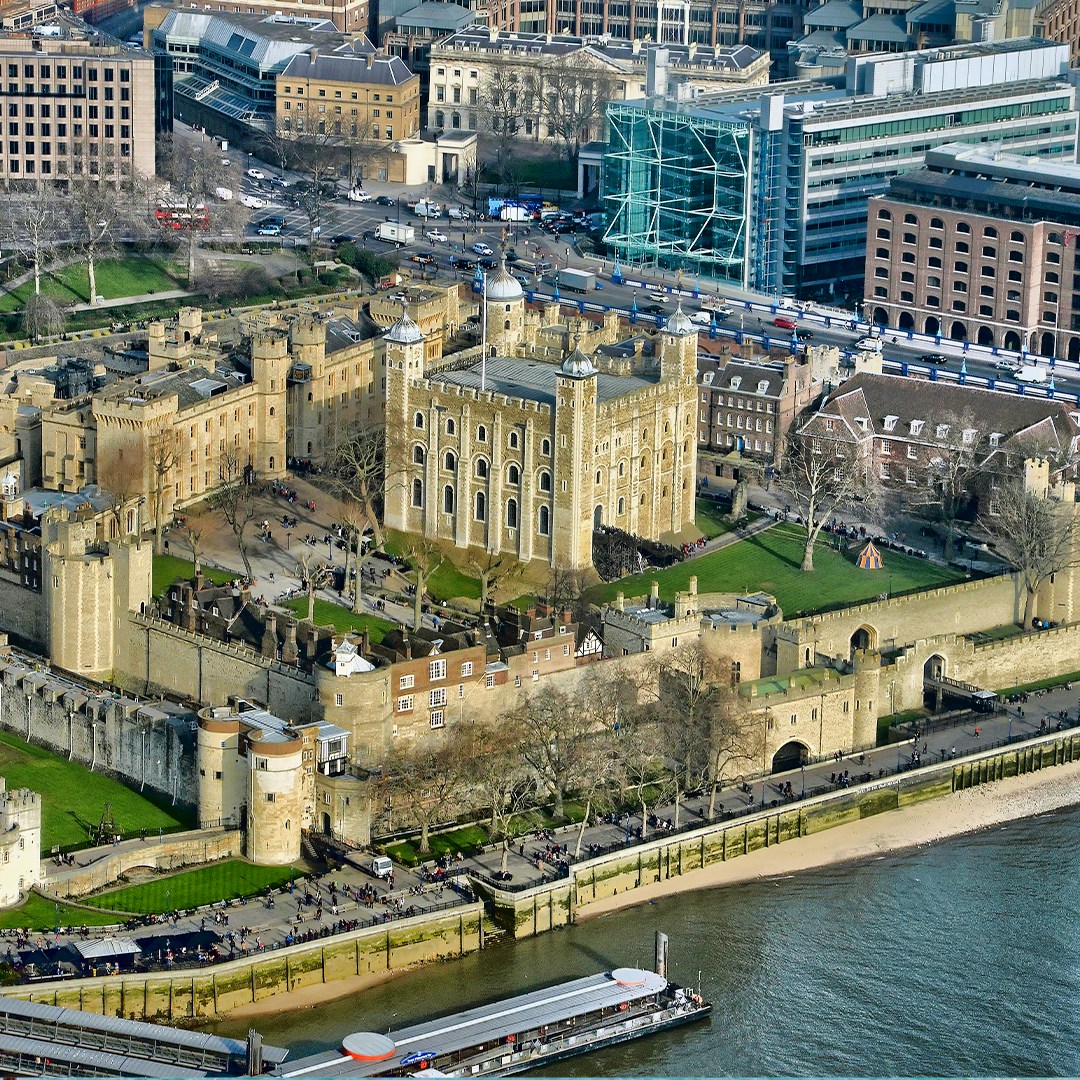 Aerial view of the Tower of London with the Thames River and nearby cruise dock.