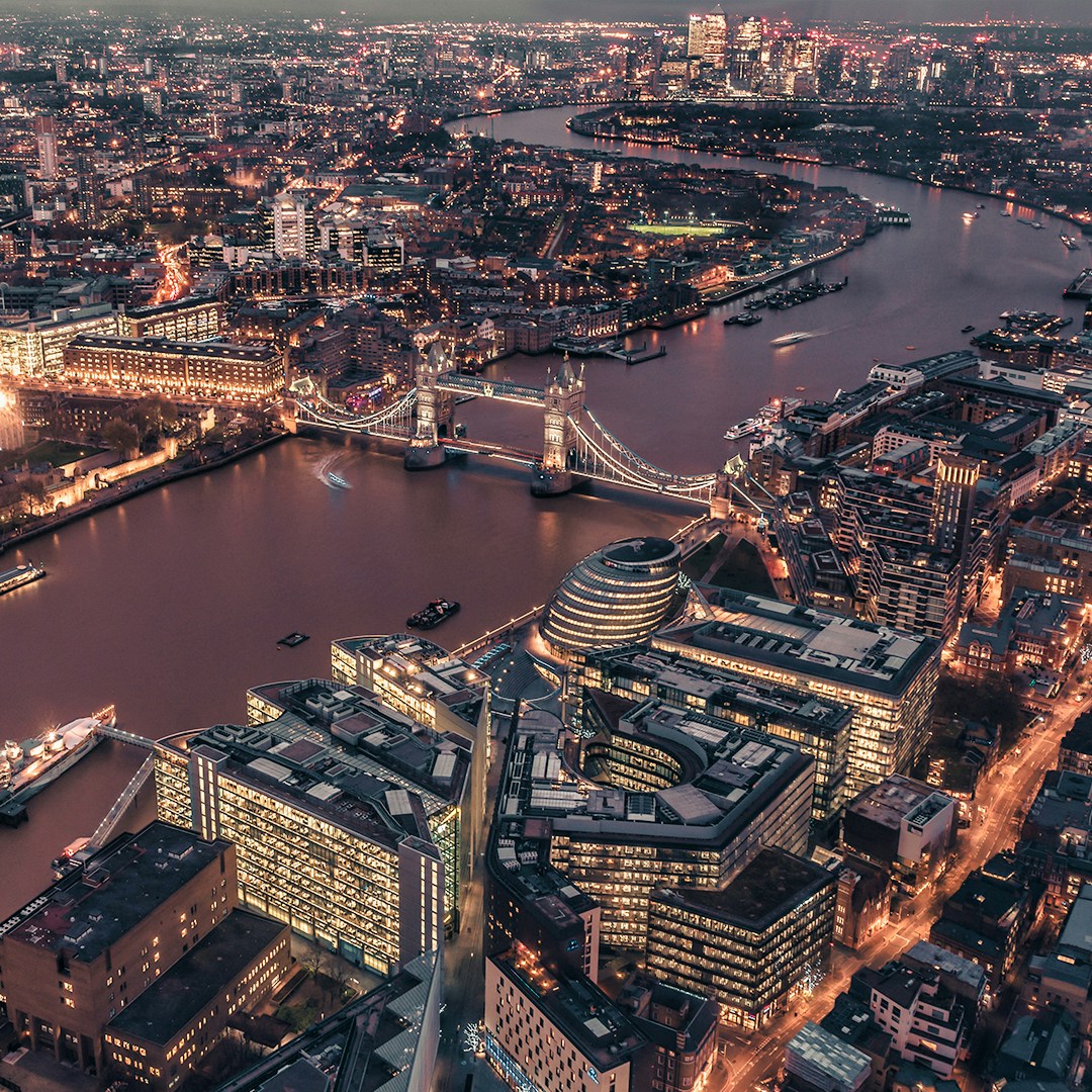 Aerial view of London at night featuring Tower Bridge and the Thames River.