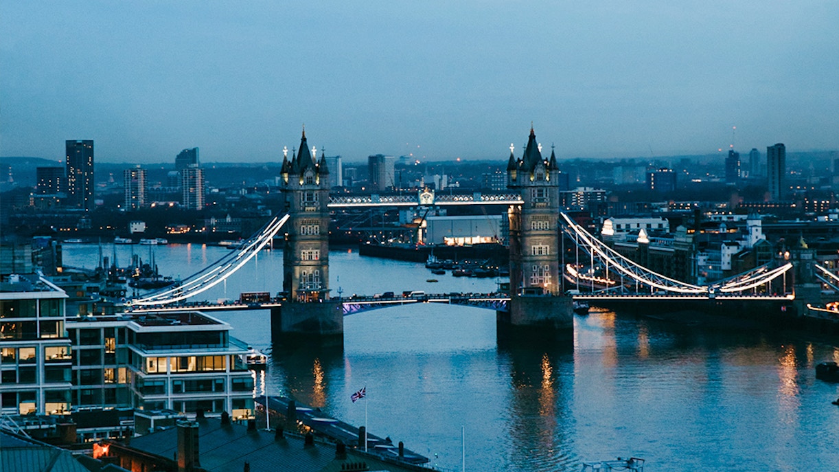 Tower Bridge illuminated at dusk over the Thames River in London.