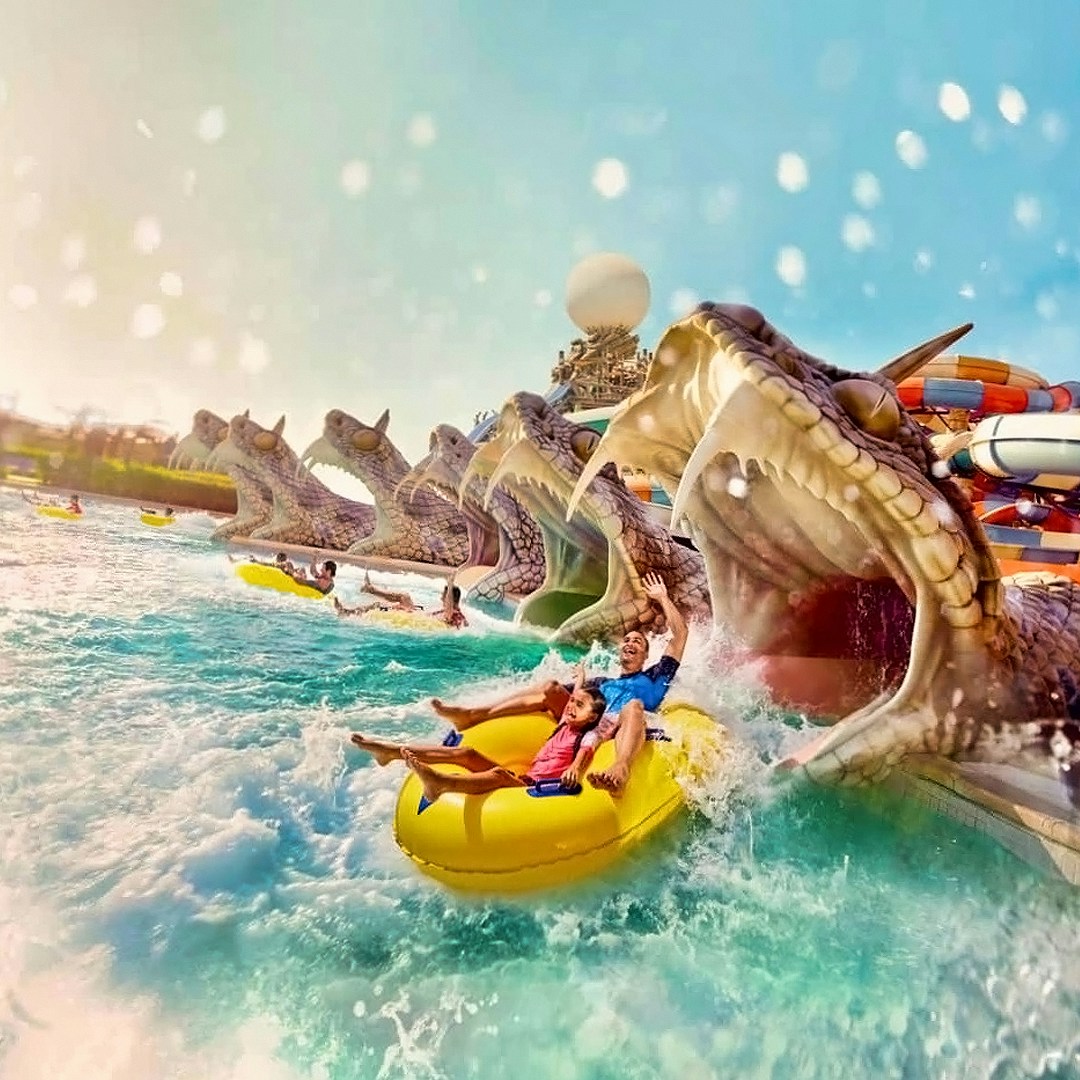 Visitors on a yellow raft exiting a snake-themed water slide at Yas Waterworld, Abu Dhabi.