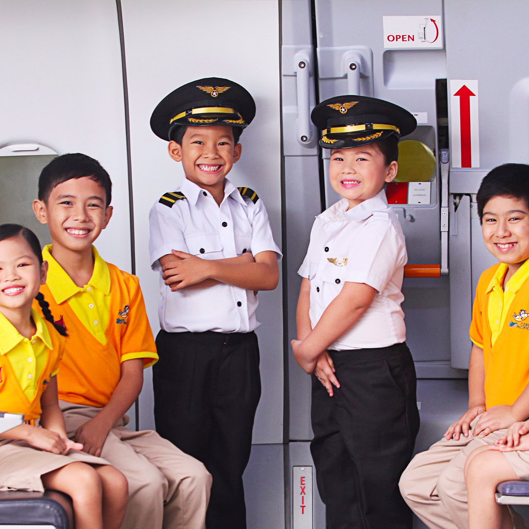 Children in pilot uniforms and yellow shirts at KidZania Singapore airplane exhibit.