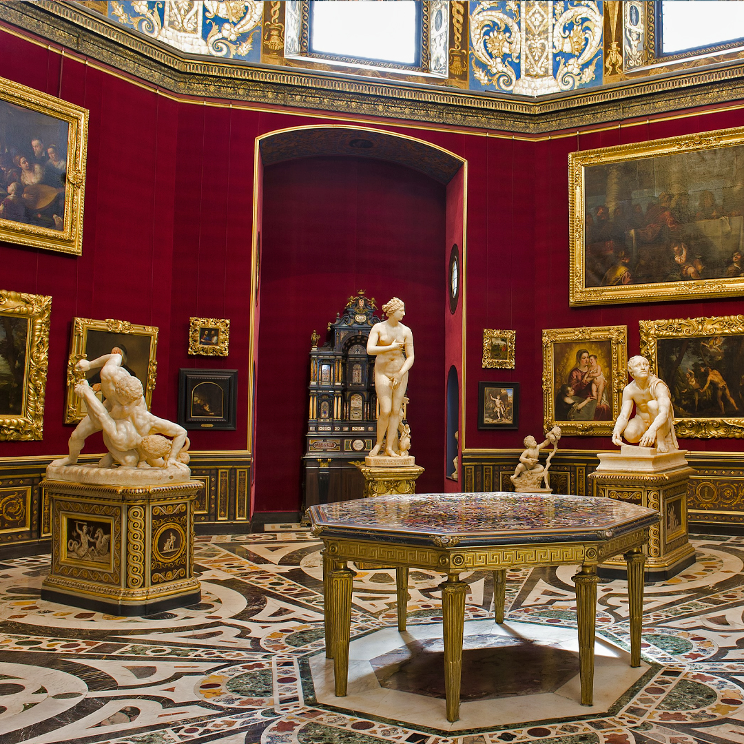 Uffizi Gallery interior with classical sculptures and Renaissance paintings in Florence, Italy.