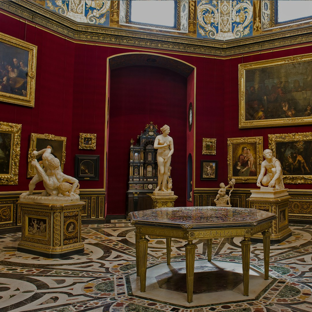 Uffizi Gallery interior with classical sculptures and Renaissance paintings in Florence, Italy.