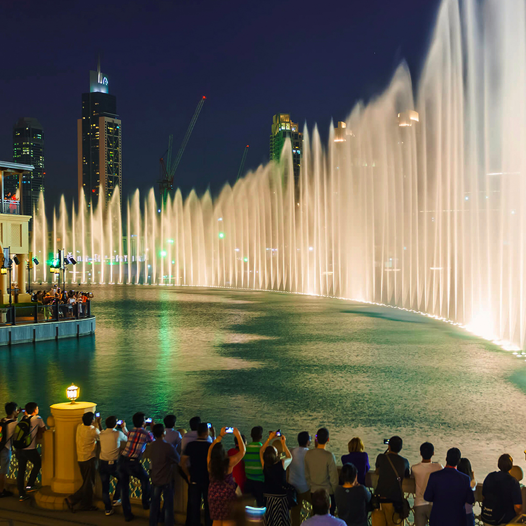 Crowd watching Dubai Fountain show near Burj Khalifa at night.