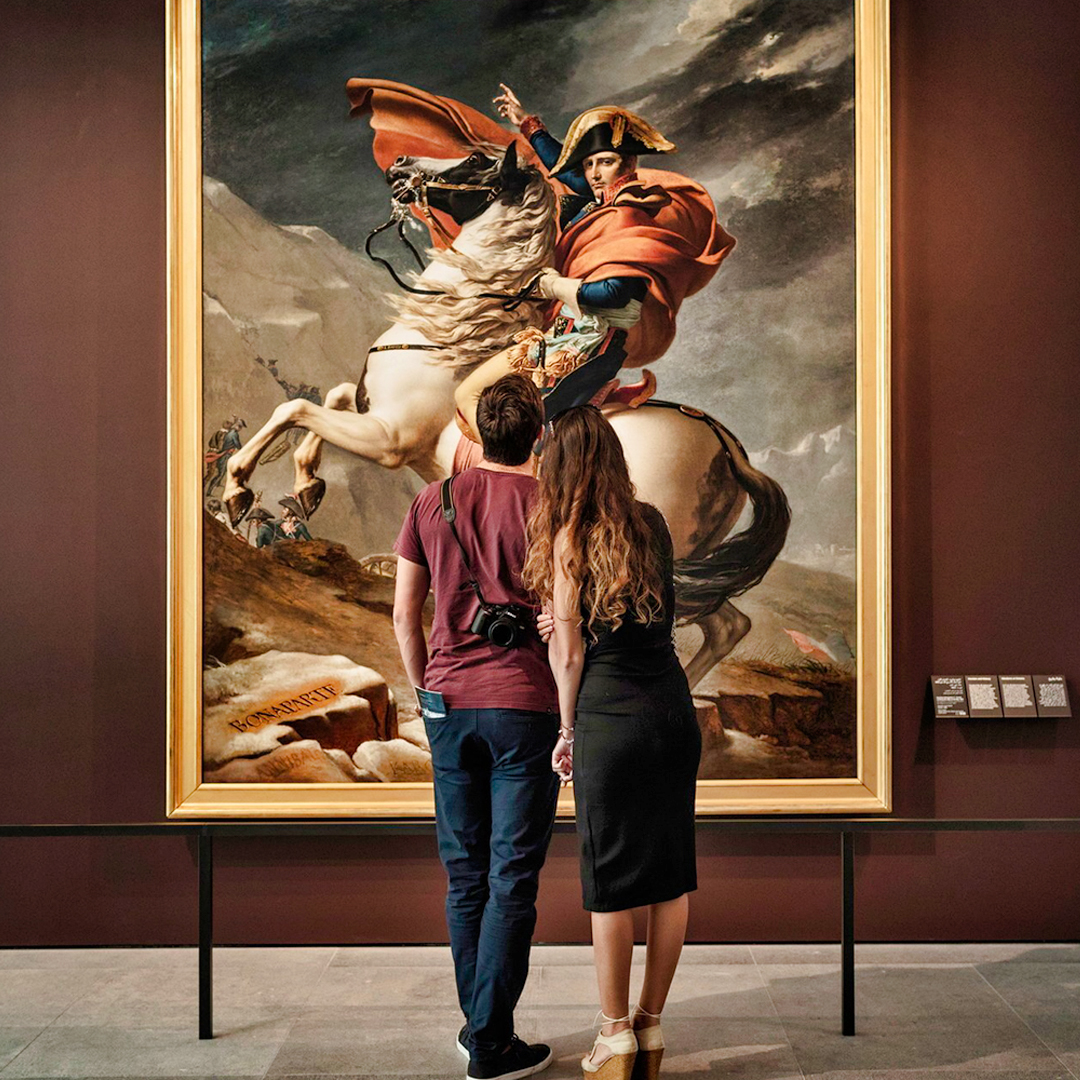 Visitors admiring Napoleon painting at Louvre Abu Dhabi during guided tour.