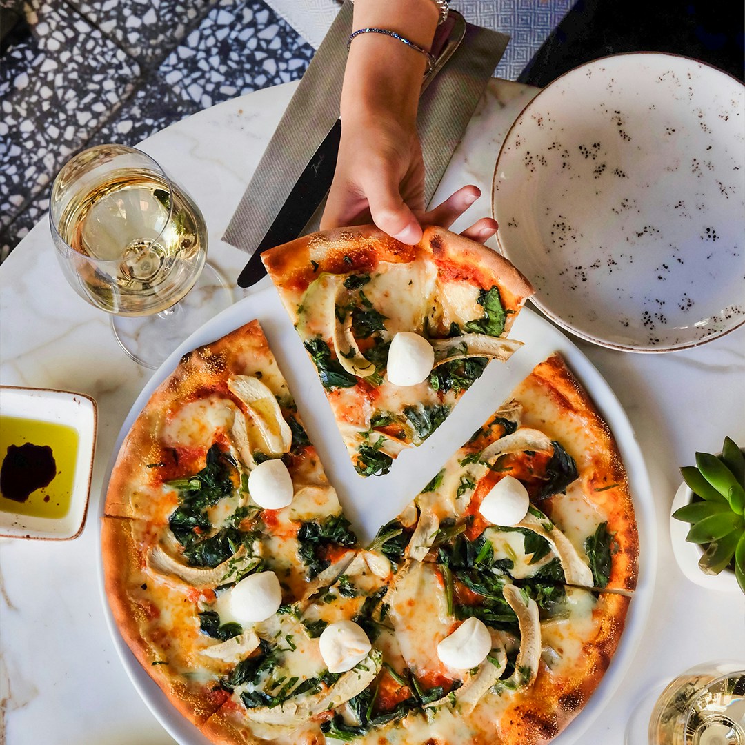 Pizza with mozzarella and greens on a table during a pizza-making course.