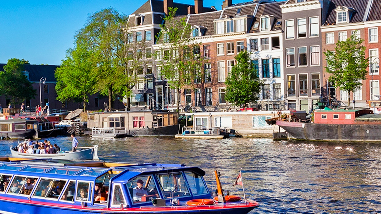 Amsterdam canal cruise boat passing historic buildings.