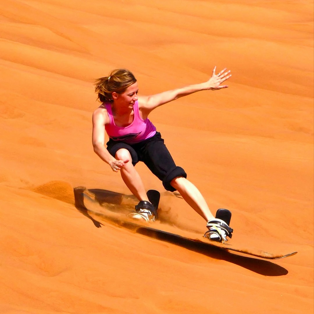 Sandboarding on desert dunes during a morning safari.