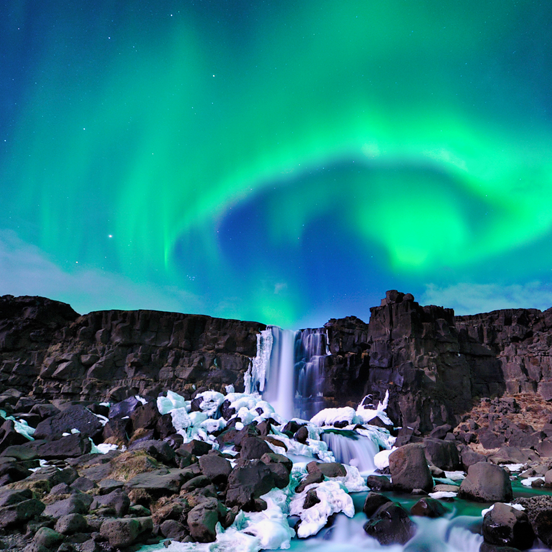 Northern Lights over waterfall near Reykjavik on Aurora Borealis bus tour.