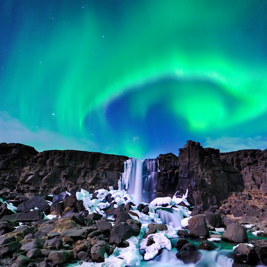 Northern Lights over waterfall near Reykjavik on Aurora Borealis bus tour.